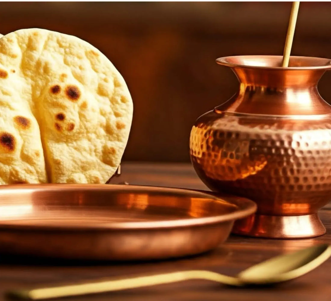 traditional Indian copper plate, jug, and spoon set with roti on a wooden table