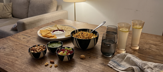 Black Carrot stoneware serving bowl, chip and dip platter, small bowls, and glasses set out for last minute hosting