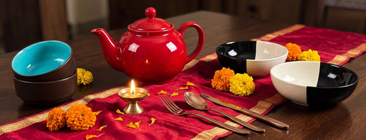 Colourful Black Carrot pieces showing the festive hues of Durga Puja — a red teapot, turquoise bowls, and gold glasses