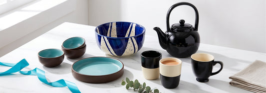 Photogenic Black Carrot gifts including black and orange mugs, a red teapot, turquoise bowls, and gold glasses