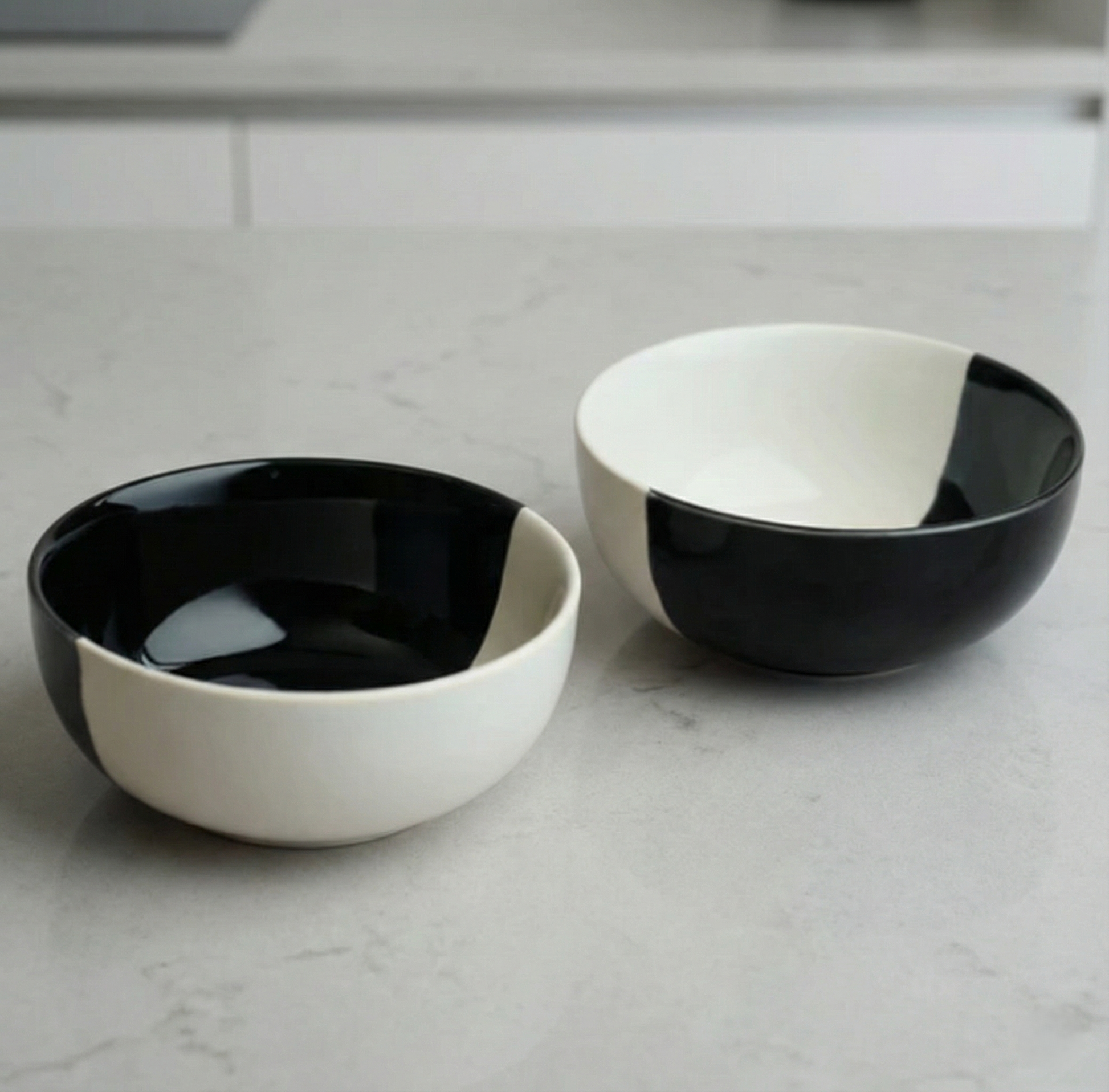 Two black and white ceramic bowls on a light gray surface.